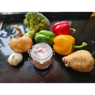 Salt i glaskrus med grönsaker på svart stenskiva